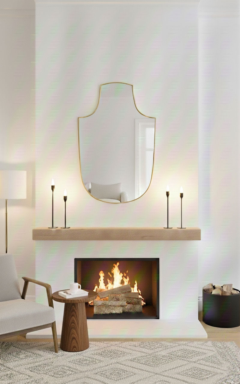 Gold arch-top shield mirror styled over fireplace mantel