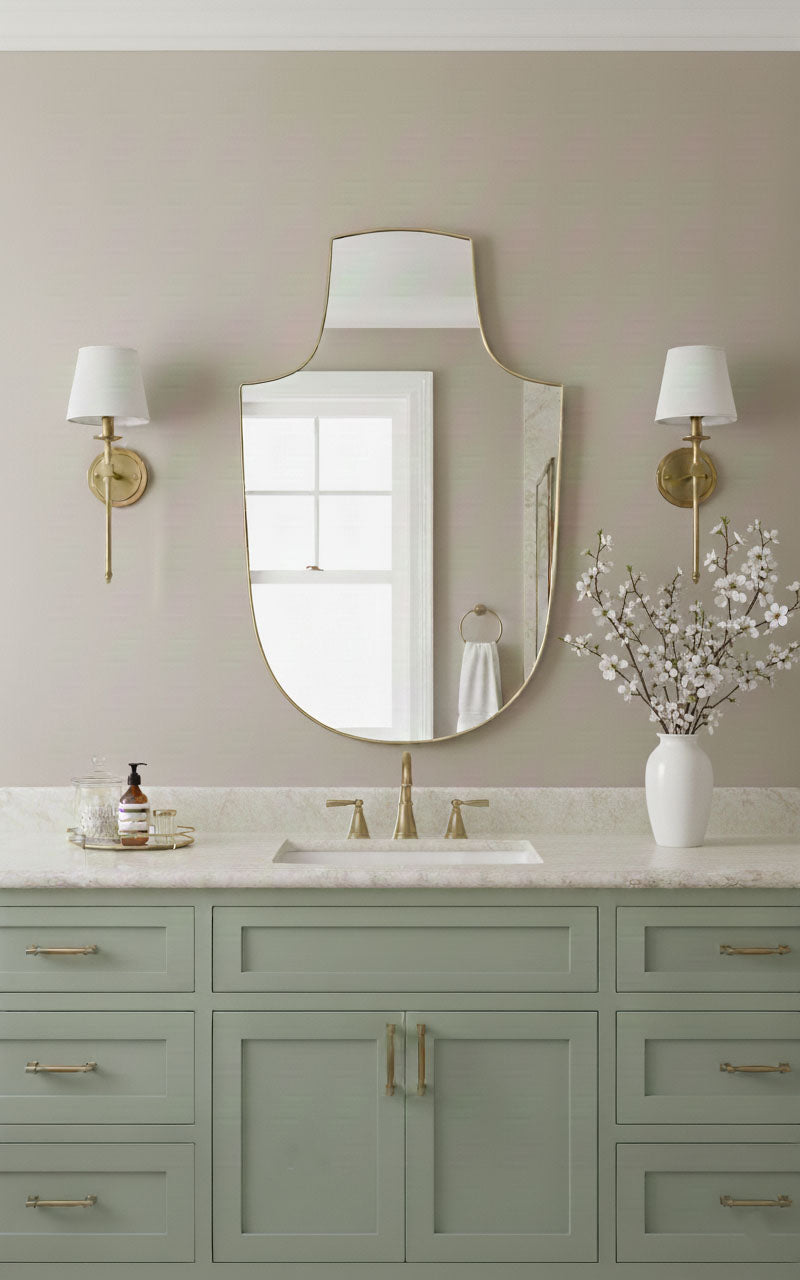 Arch-top shield brass mirror with wall sconces above vanity