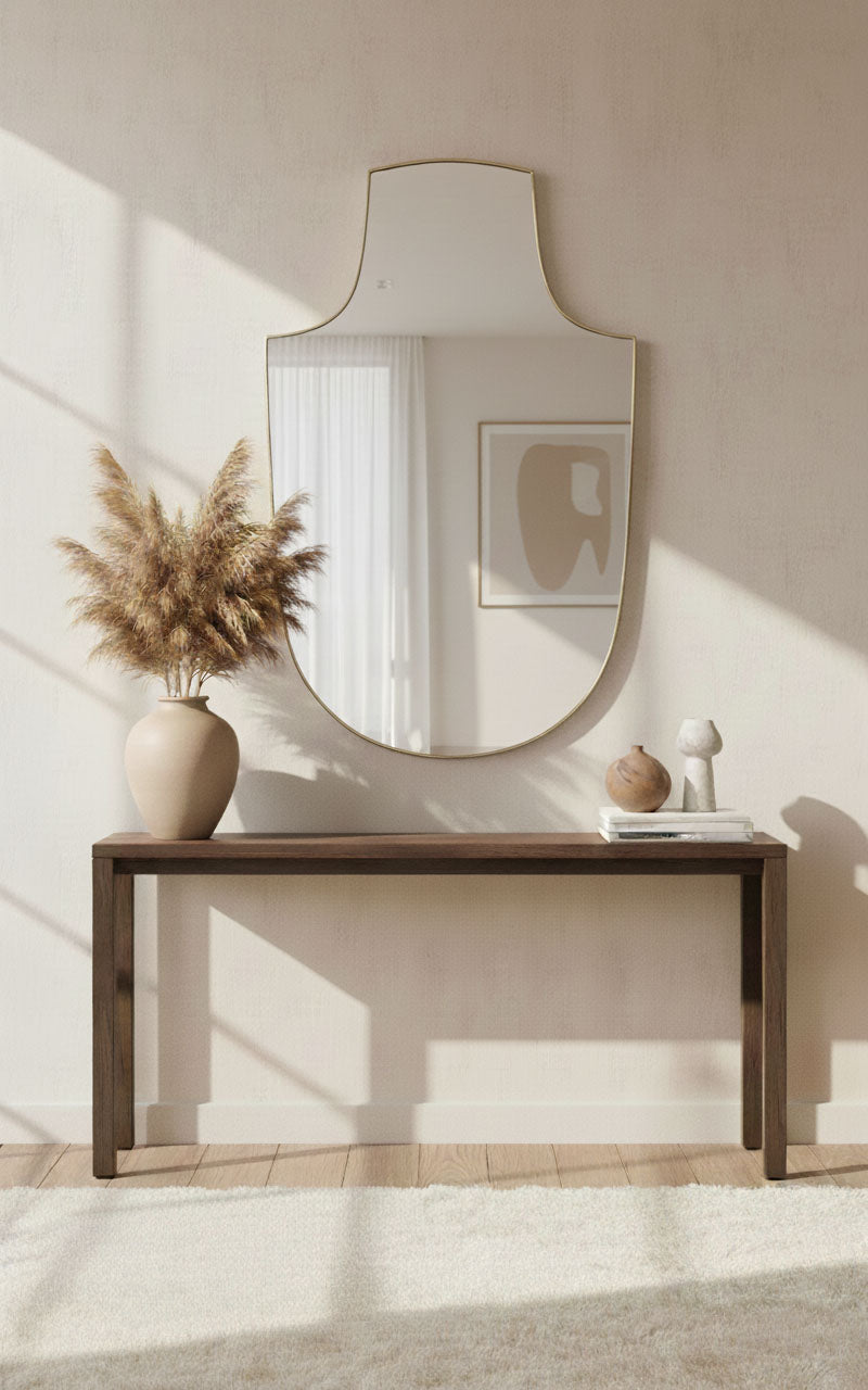 Gold arch-top shield mirror displayed above console table
