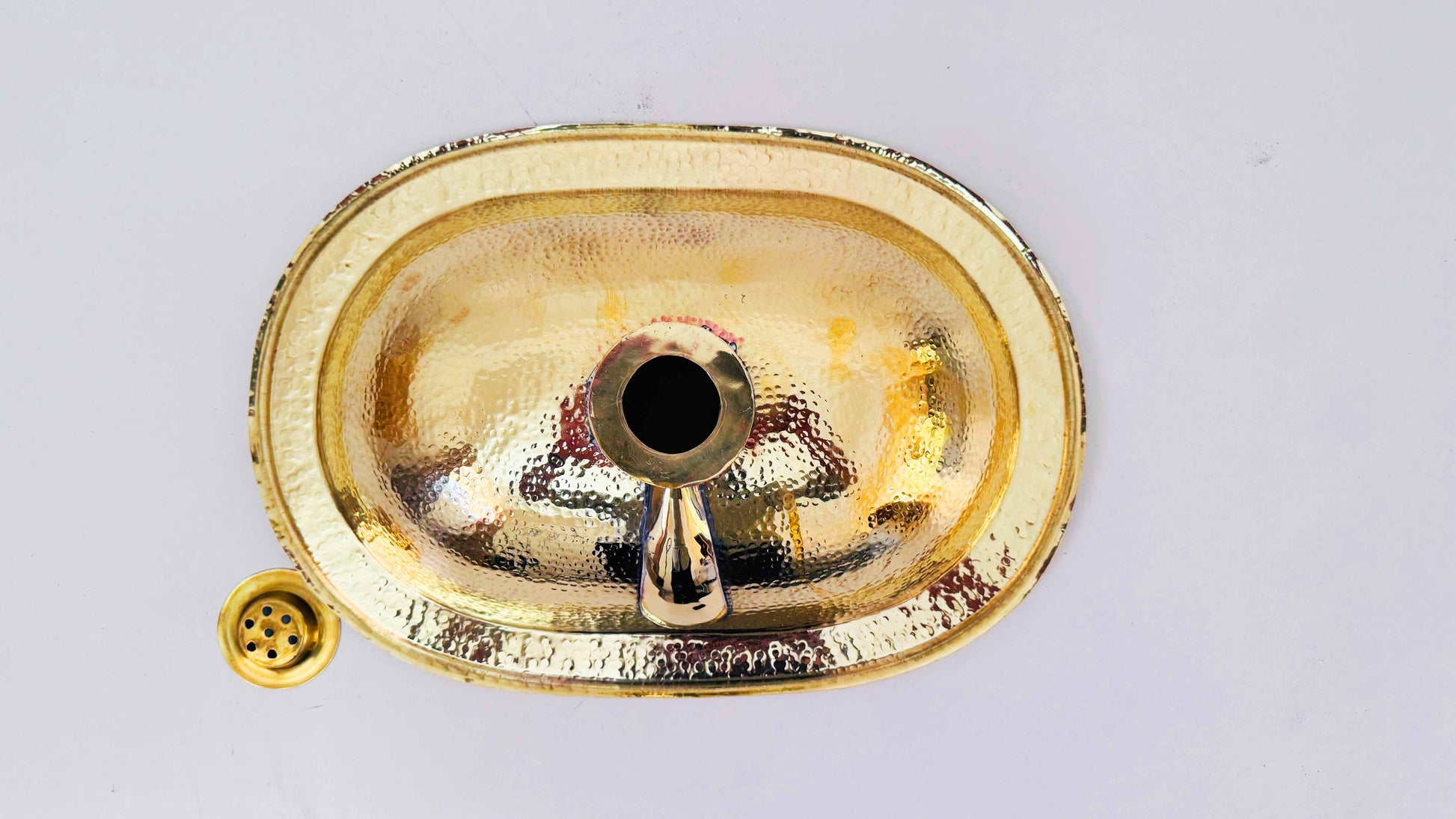 a gold sink with a black drain in the middle of it