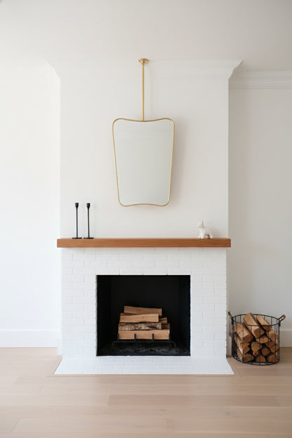 Suspended brass butterfly mirror above a white mantel fireplace