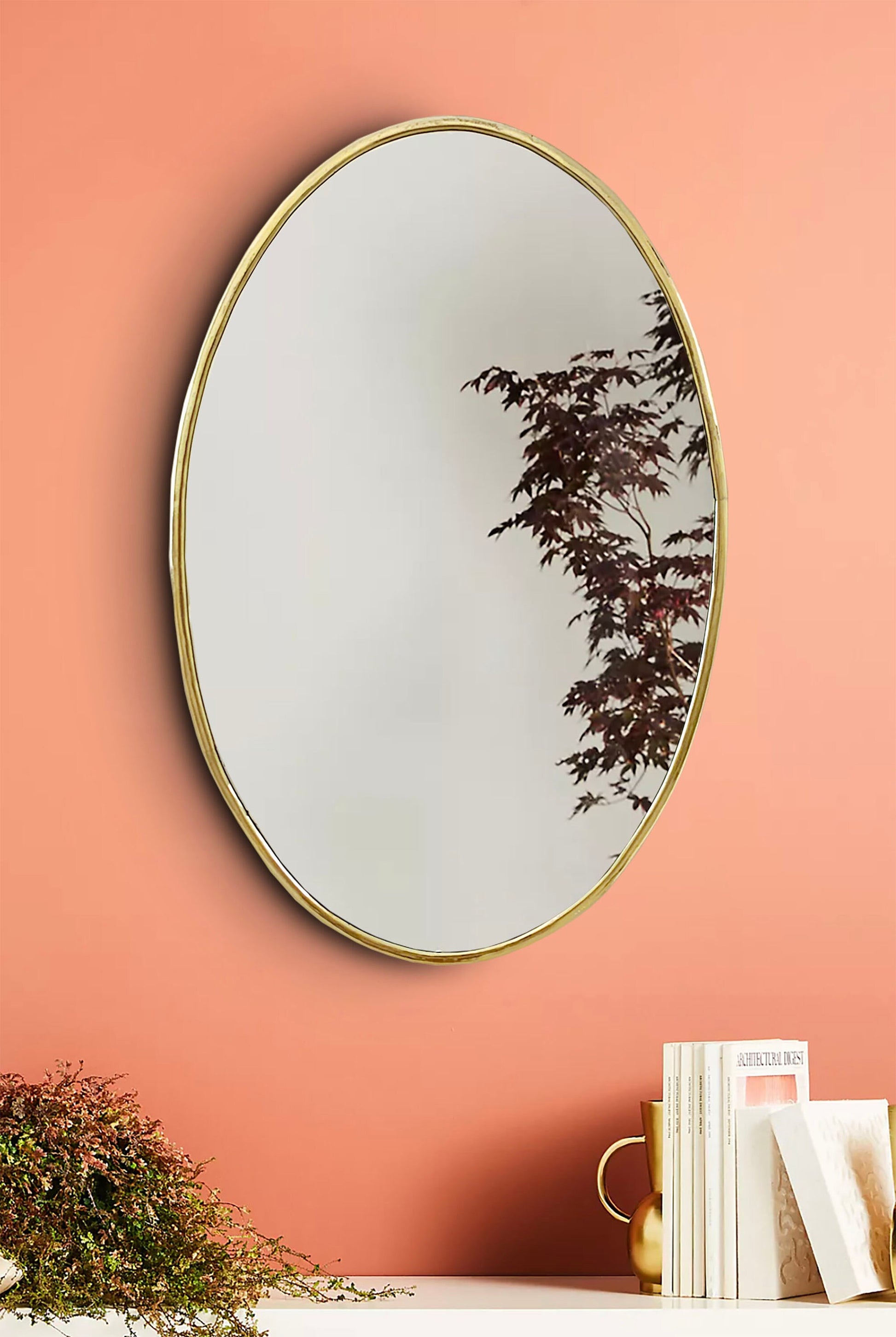 a round mirror hanging on a pink wall