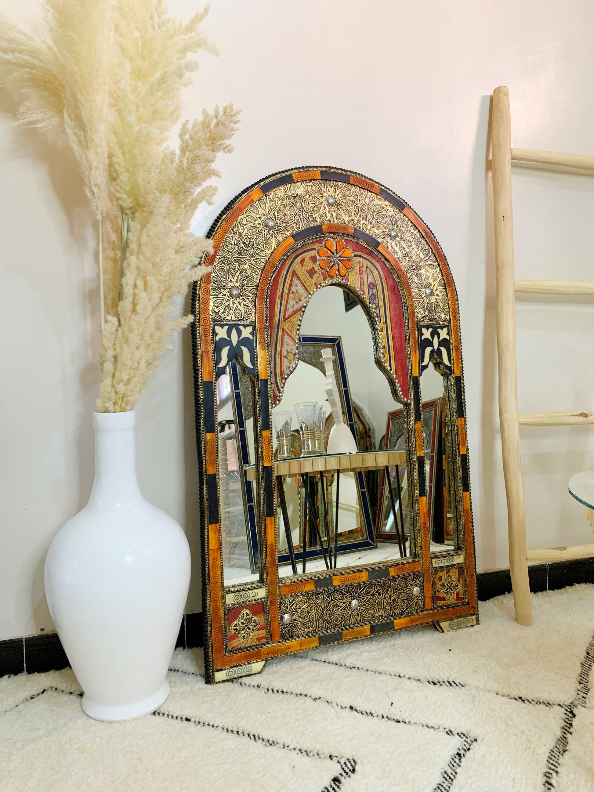 a white vase sitting next to a mirror on a floor