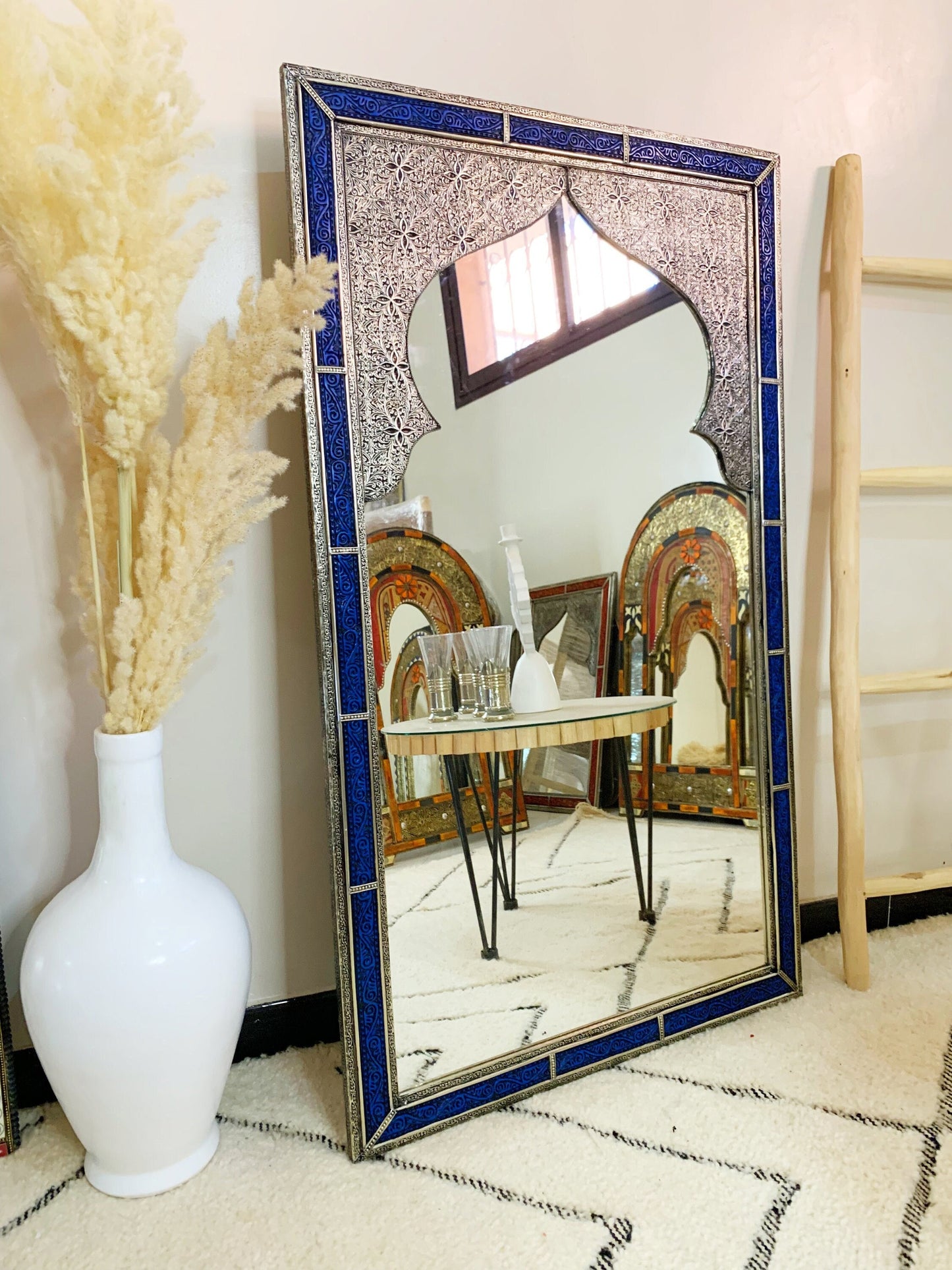 a mirror sitting on top of a floor next to a vase