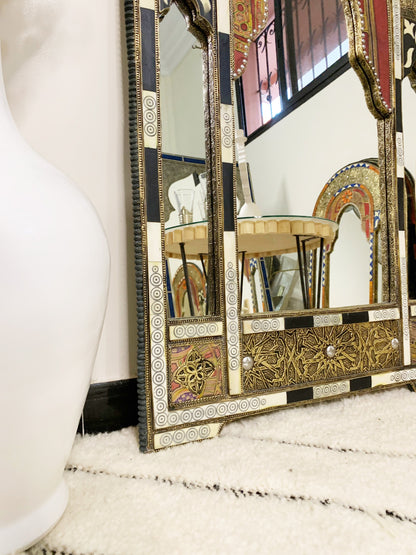 a mirror sitting on top of a table next to a vase