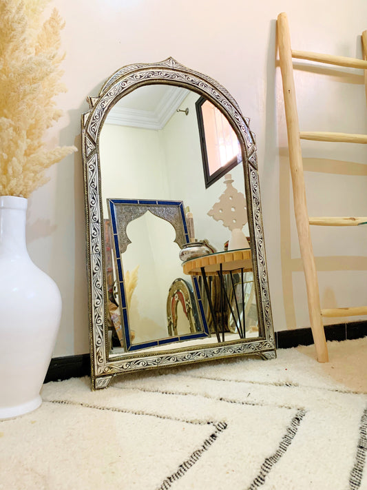 a mirror sitting on the floor next to a vase