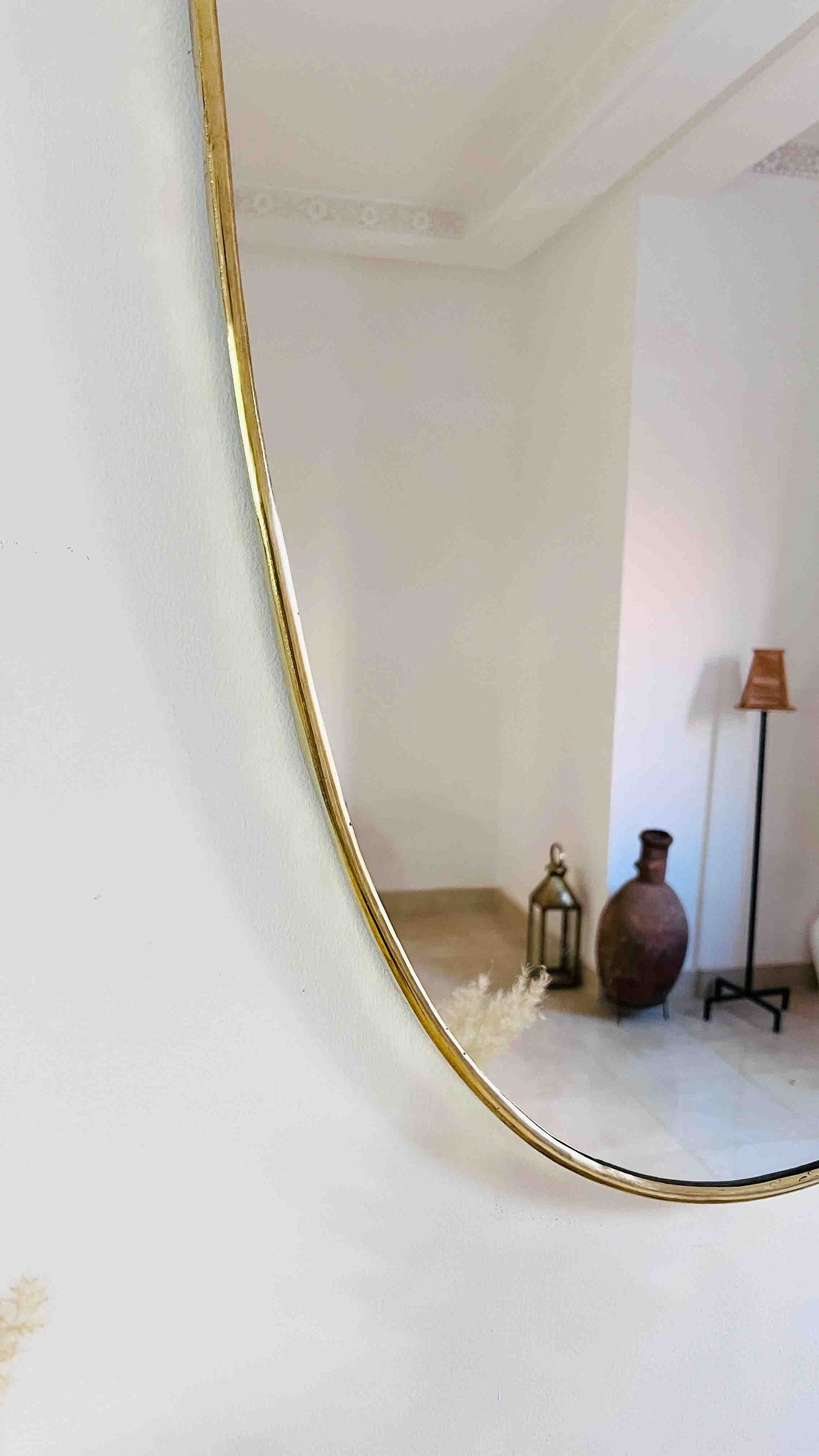 a mirror reflecting a room with a vase on the floor