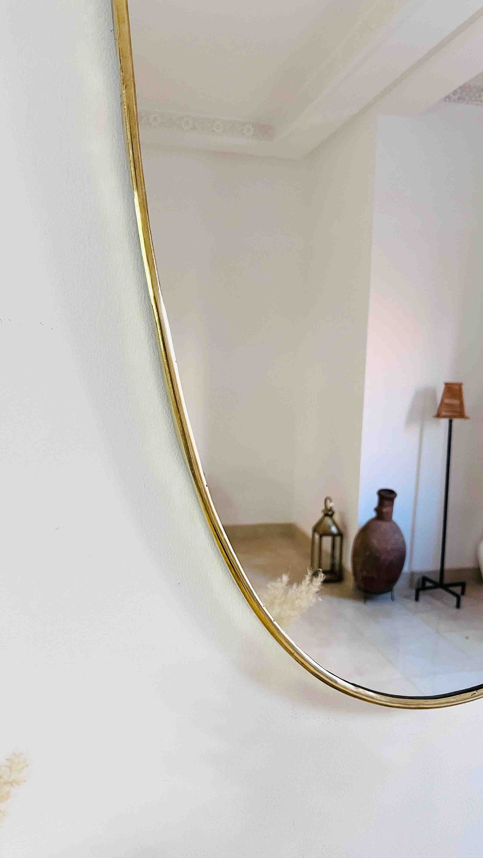 a mirror reflecting a room with a vase on the floor